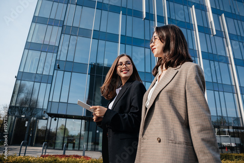 Business professionals walk outside a modern office building while discussing new projects in the city during daylight hours