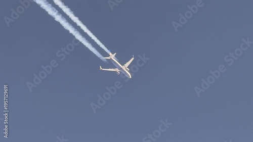 Aerial cockpit view of the botton of a jet airplane and a fading contrail flying in a deep blue sky. Scene captured from a jet cokpit flying bellow.
