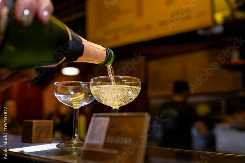 Pouring sparkling wine into coupe glass at lively bar