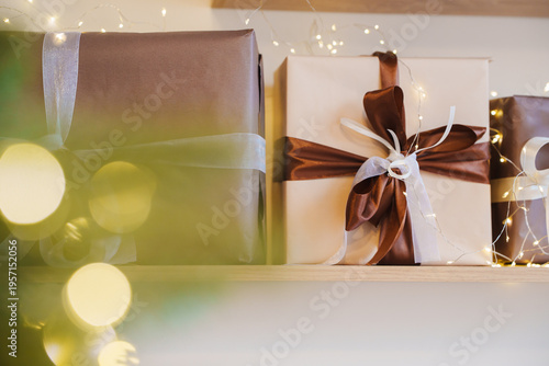 Wrapped gifts on shelf with lights and greenery during holiday season