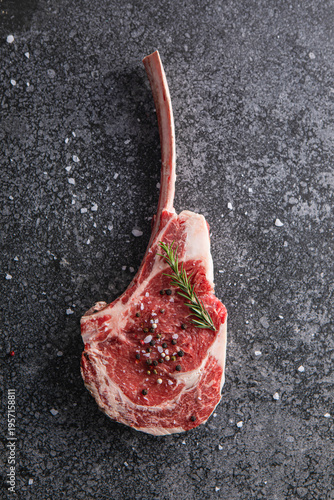 Canvastavla Raw tomahawk ribeye steak with fresh rosemary, sea salt, and peppercorns