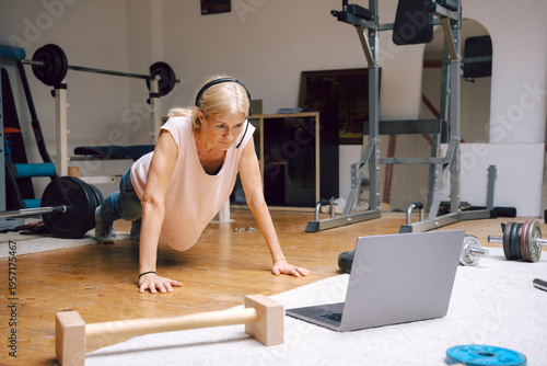 Woman exercising with a laptop and headset in a home gym
