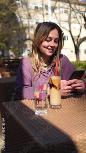 Young woman in a cafe outdoors using a mobile phone