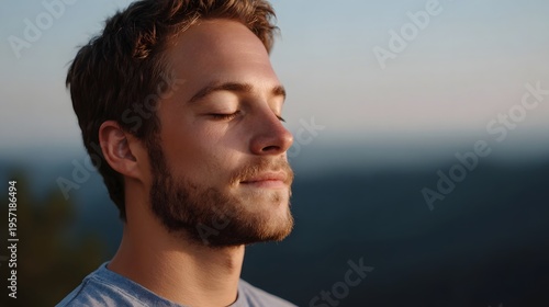Close up of a man meditating peacefully outdoors with a serene mountain vista in the background at sunset