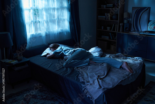 Obraz na płótnie Young woman lying on bed facing away from camera, resting with head on pillow in