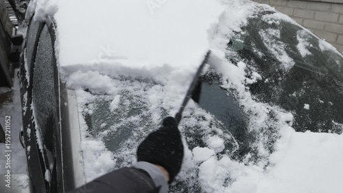 Man cleaning snow from car after heavy snowfall in winter.