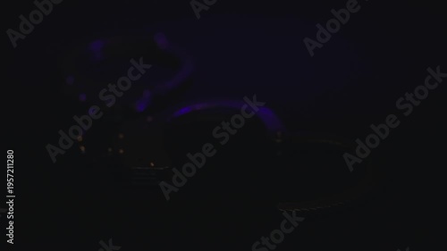 Closed handcuffs on a dark background, illuminated with mixed red and blue light, close-up.