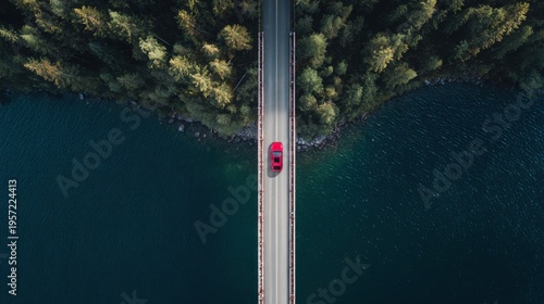 Aerial view of a red car driving on a bridge over a lake