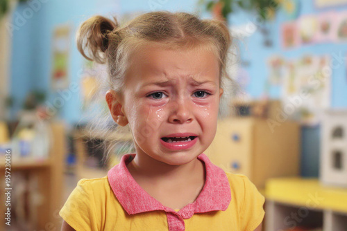 A young child with tearful eyes cries in a classroom setting, captured in a close-up that emphasizes emotion, vulnerability and early childhood distress.