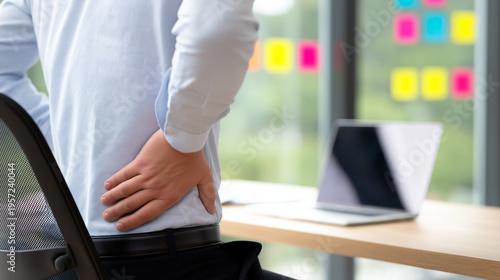Office worker experiencing chronic back pain from prolonged sitting at a desk, indicating poor posture, a sedentary lifestyle, and needing ergonomic improvement