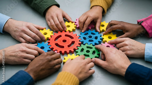 Diverse group of people working together with colorful gear puzzle pieces on a table, symbolizing teamwork and collaboration.