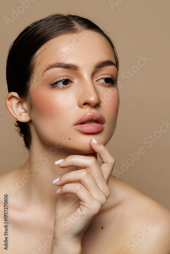 Beautiful young woman with clean fresh skin on beige background,