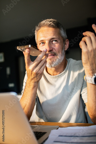 Middle-aged man using voice assistant at home office