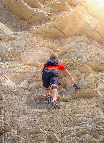 A young, athletic man climbs a mountain, overcoming difficulties and resistance