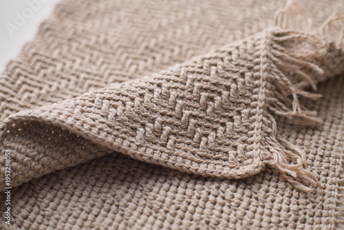 Close-up of a soft, beige crochet towel featuring intricate texture and fringed edges, perfect for bath, home decor, or textile design projects.
