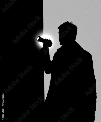 Silhouette of a man holding a flashlight and illuminating a wall in a dark environment image