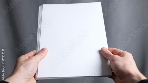 Male hands hold blank white A5 flyers mid-air against a soft grey background in a clean invitation mockup presentation.
