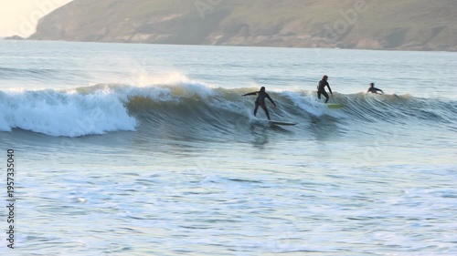 Pan of surfers catching waves in the surf mecca of Croyde in Devon at sunset, one of the best surf breaks in Europe