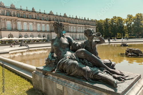 View of the Latona Fountain in front of Herrenchiemsee Palace, featuring a dramatic mythological sculpture rising from the water with the grand palace façade in the background