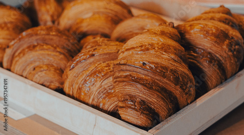 Freshly baked croissants arranged in a wooden tray on display