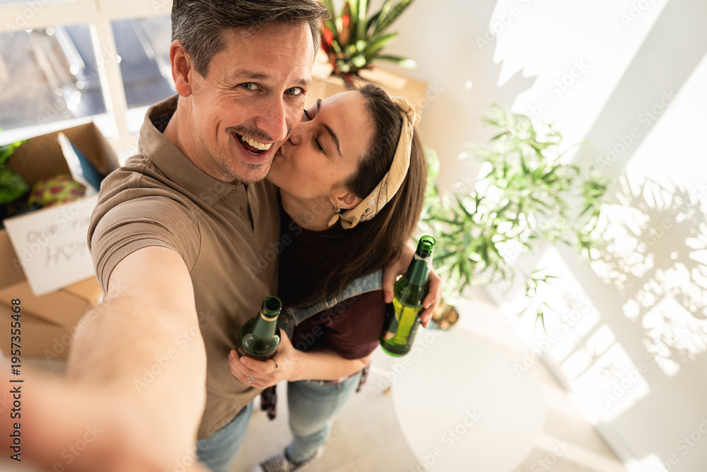 Fototapeta premium Couple enjoys time together while holding drinks in a bright indoor space during a home celebration