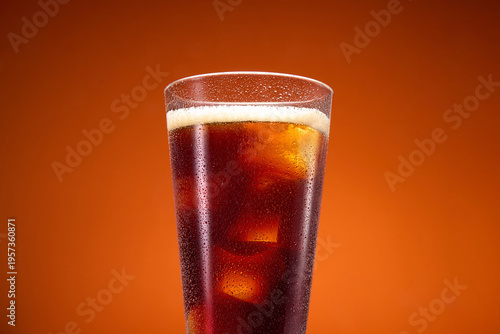 Glass of Cola with Ice Cubes on Orange Background