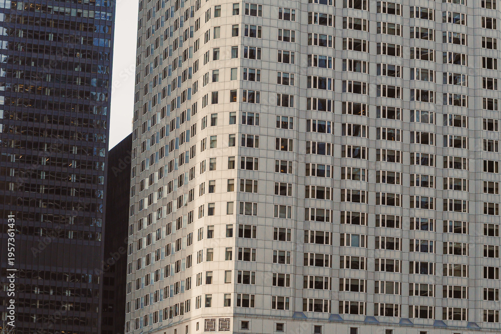 Fototapeta premium Modern buildings stand in a city during late afternoon with sunlight brightening the windows and creating shadows
