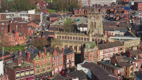 WIGAN, GREATER MANCHESTER, ENGLAND - MARCH 18, 2026: Aerial view of Wigan town centre with the Parish Church and the indoor market hall, slow approach