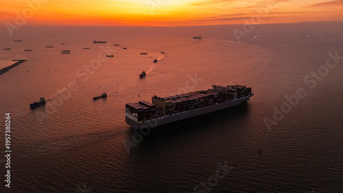 Aerial view of a large container cargo ship sailing across surrounded by multiple vessels along busy international shipping routes.
