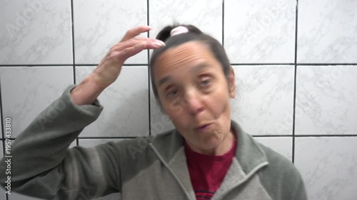 Kas, Turkey - 9 of February 2026: 4K Middle-aged woman examining her graying hair in the mirror
