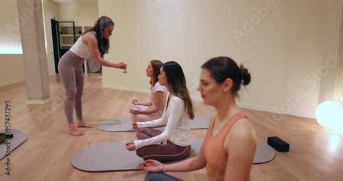 Yoga instructor offering a glass of wine to a student during a mindful meditation class, a unique spiritual practice combining relaxation, sensory awareness, and wellness in a modern studio