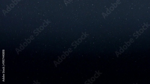 Gentle particles float across a dark gradient background creating a moody and atmospheric abstract scene.