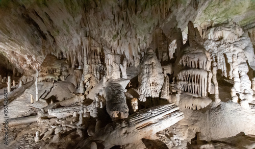 Limestone cave interior with stalactites and stalagmites illuminated in underground chamber