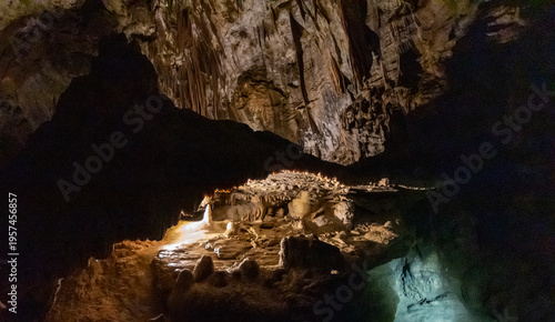 Limestone cave interior with stalactites and stalagmites illuminated in underground chamber