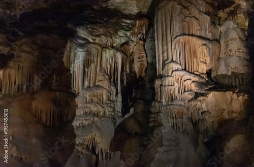 Limestone cave interior with stalactites and stalagmites illuminated in underground chamber