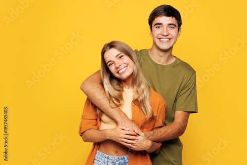 Young smiling calm couple two friends family man woman wear shirt casual clothes cuddle embrace look camera together isolated on pastel plain light yellow background studio portrait Lifestyle concept