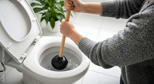 Person using a plunger to unclog a toilet bowl
