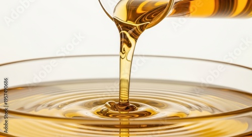 Golden liquid elegantly flowing into a reflective surface from a glass vessel