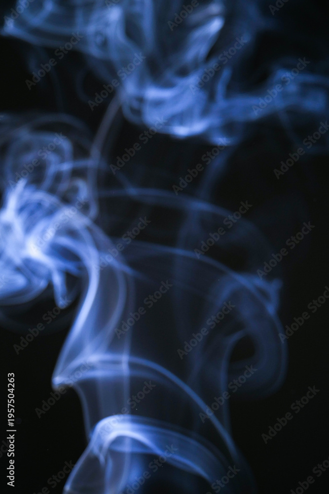 Obraz premium Delicate blue smoke swirling against a dark backdrop, creating an abstract and ethereal effect. The wisps of smoke dance and weave, forming intricate patterns