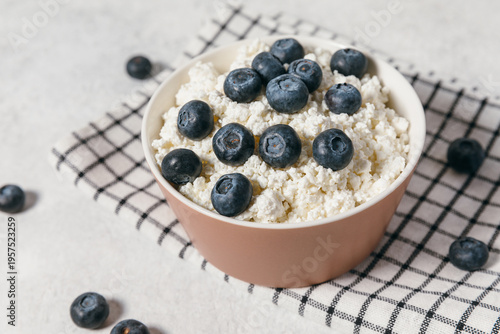 Photos Fresh cottage cheese with blueberries in ceramic bowl on a grid-patterned napkin
