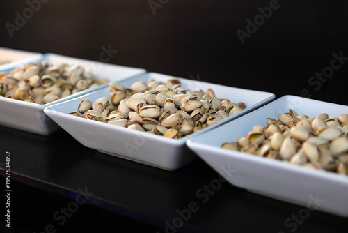 Bowls filled with empty pistachio shells are displayed on a black surface during a gathering in a social setting