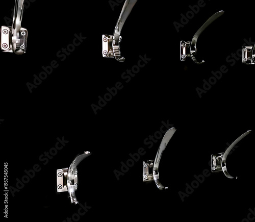 Chrome metal clothes hooks hanging on a black wall