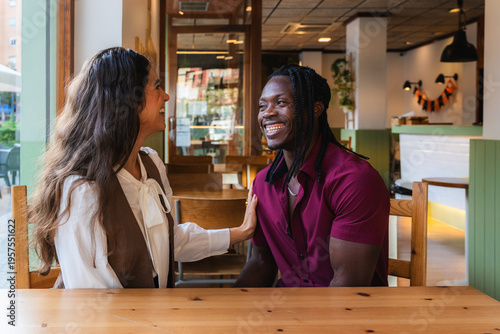 Happy multiracial couple smiling and talking at a restaurant table