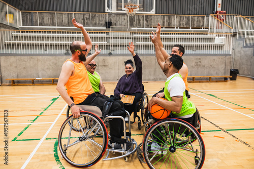 Athletes in wheelchairs raising hands, celebrating victory on the court with female coach, showing teamwork and sports inclusion