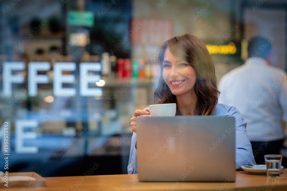 © sepy - Mid aged woman usa cafe and photographed through a window