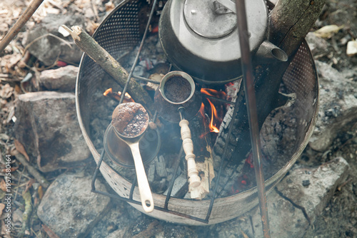 the kettle and the  turkish coffee pot on a fire  at a campsite surrounded by stones during daylight hours