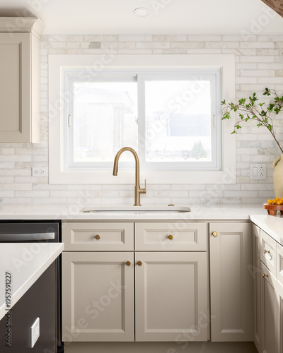 A kitchen detail with brown cabinets, marble subway tile backsplash, gold faucet, and decorations on the marble countertop.