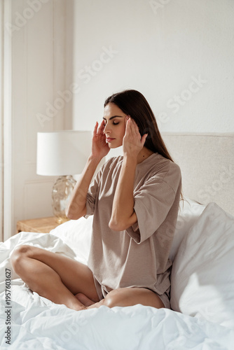 Beautiful young woman enjoying quiet morning at home in bed practicing relaxation and self-care routine.  Mindfulness, stress felief, headache, mental health, slow living lifestyle