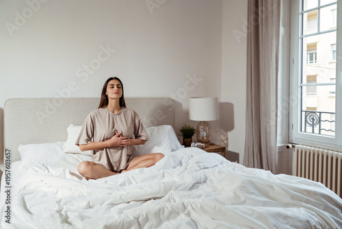 Calm young woman practicing deep breathing meditation at home in bedroom. Mindfulness, emotional balance, anxiety relief, nervous system regulation, breathwork  concept