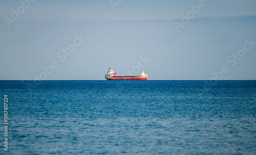 Cargo ship on calm blue sea under clear sky